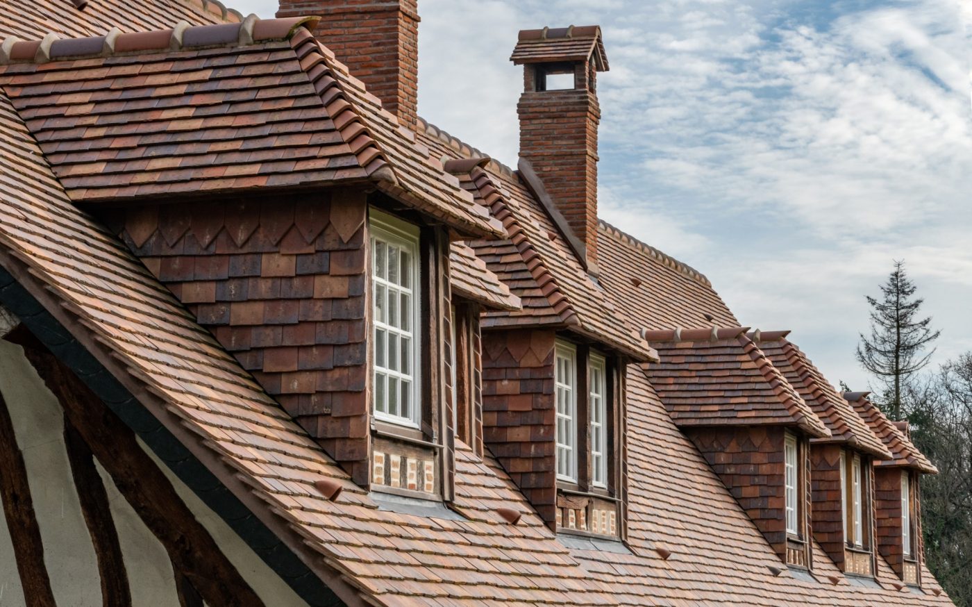 photo d'une toiture d'un manoir en Normandie avec les tuiles Patrimoine Rectangulaire Ocré Lichen, Vert de Lichen, Rouge de Mars